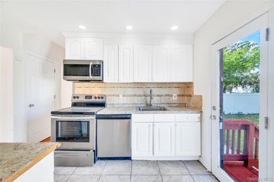 Kitchen featuring appliances with stainless steel finishes, tasteful backsplash, white cabinets, light tile patterned floors, and recessed lighting