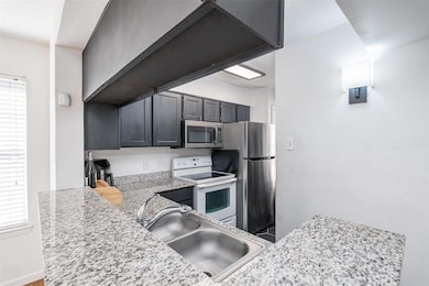 Kitchen with light stone counters, sink, plenty of