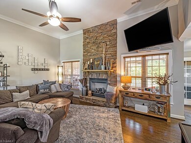 Large living room with 12' ceilings, stone gas log fireplace, views of the backyard and hardwood floors