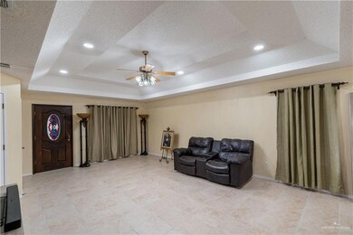 Living area featuring a tray ceiling, a ceiling fan, a textured ceiling, recessed lighting, and light tile patterned flooring