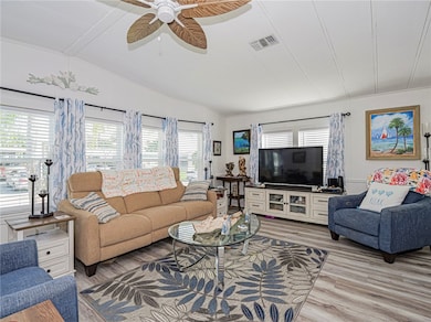Living area with healthy amount of natural light, light wood finished floors, vaulted ceiling, and ceiling fan