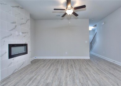Unfurnished living room with light wood-style flooring, a tile fireplace, a ceiling fan, and stairs