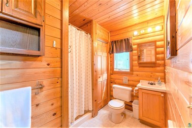 Bathroom featuring wood ceiling, log walls, toilet