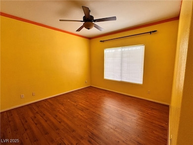 Unfurnished room featuring dark wood-style flooring, crown molding, and ceiling fan