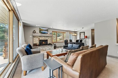 Living area with a stone fireplace, a baseboard radiator, a textured ceiling, light carpet, and a baseboard heating unit