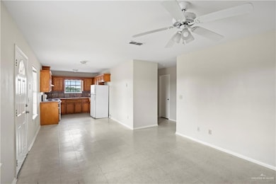 Kitchen featuring white appliances, brown cabinetry, open floor plan, decorative backsplash, and a ceiling fan