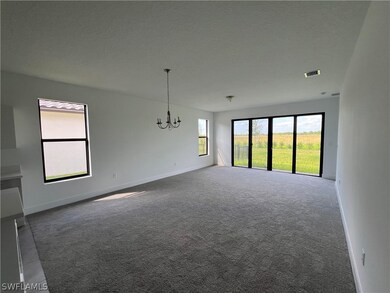 Carpeted empty room featuring an inviting chandeli