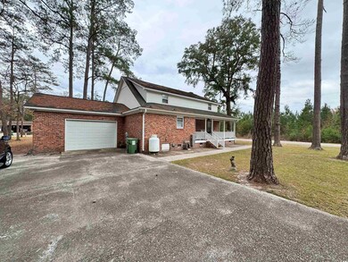 View of back of house with a garage, covered porch, and a front lawn