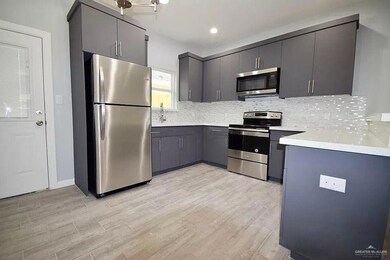 Kitchen featuring stainless steel appliances, light wood-style flooring, gray cabinetry, and decorative backsplash