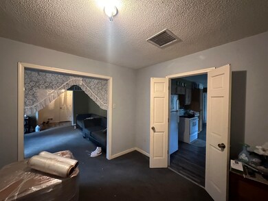 Carpeted bedroom with white fridge and a textured 