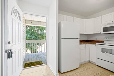 Kitchen with light tile patterned floors, white ca