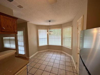 Unfurnished dining area with light tile patterned floors, a chandelier, a textured ceiling, and baseboards