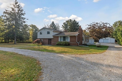 Split level home with brick siding, a chimney, a front lawn, and driveway