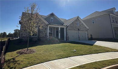 View of front of house featuring driveway, stone siding, a garage, a front lawn, and covered porch
