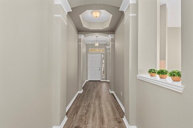 This view toward the front door shows the fresh paint, newly installed vinyl plank flooring and all the charm from the special touches including crown molding and arched entryways.