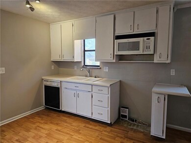 Kitchen with white microwave, light wood-style flo