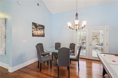 Dining space featuring a chandelier, wood finished floors, french doors, and high vaulted ceiling