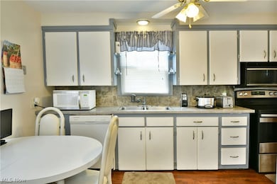Kitchen with dark hardwood / wood-style floors, white cabinets, and white appliances