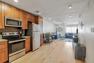 Kitchen featuring appliances with stainless steel finishes, light wood finished floors, a ceiling fan, light stone countertops, and backsplash