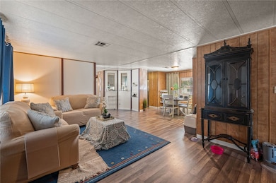 Living area with wooden walls, wood finished floors, and a textured ceiling