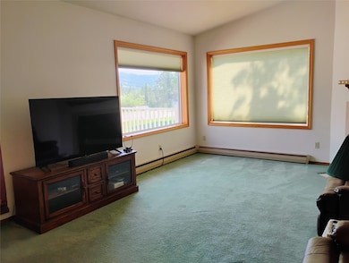 Unfurnished living room featuring carpet and baseboards
