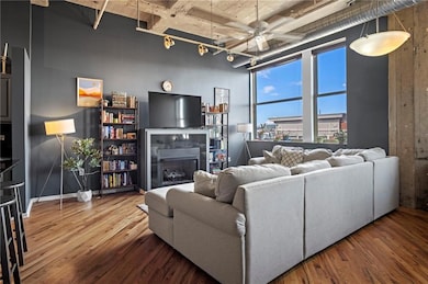 Living area with a ceiling fan, a tile fireplace, track lighting, and wood finished floors