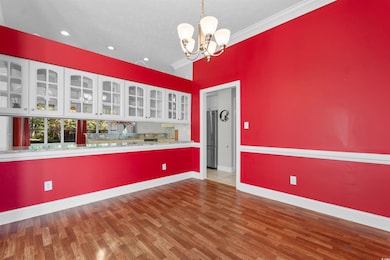 Spare room with a chandelier, dark wood-style floors, and crown molding