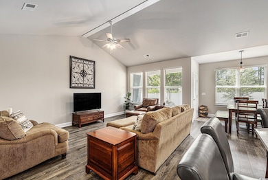 Living area with dark wood finished floors, baseboards, a ceiling fan, and healthy amount of natural light