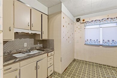 Kitchen with cream cabinetry, decorative backsplash, dark stone counters, and tile walls