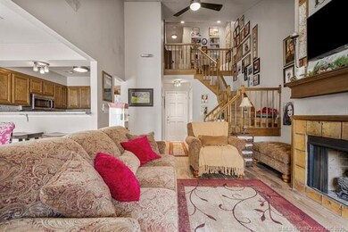 Living room with a ceiling fan, stairs, wood finished floors, a fireplace, and a high ceiling