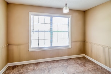 Spare room with wainscoting, a textured ceiling, and light tile patterned floors
