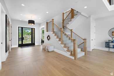 Entrance foyer featuring light wood-style floors, stairs, baseboards, and recessed lighting