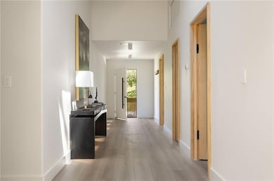 Corridor featuring light wood finished floors, a skylight, arched walkways, and high vaulted ceiling