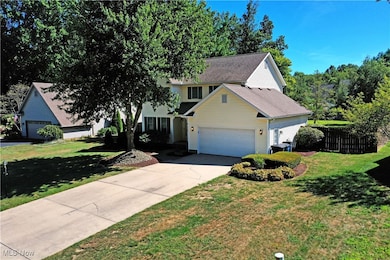 Traditional-style home with a garage, driveway, and roof with shingles