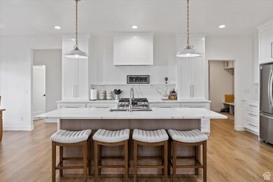 Kitchen with recessed lighting, a sink, freestanding refrigerator, light wood-type flooring, and white cabinetry