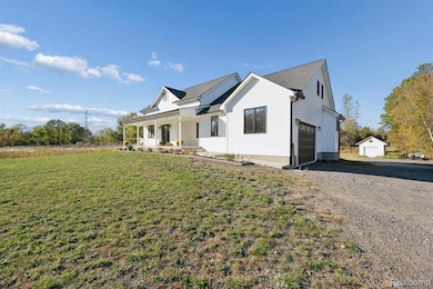 View of front of house with a garage, covered porch, a front lawn, and gravel driveway
