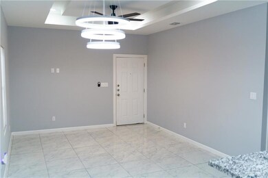 Spare room featuring a tray ceiling, light marble finish floors, and ceiling fan