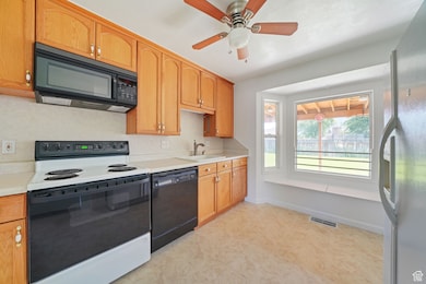 Kitchen with black appliances, light countertops, and a ceiling fan