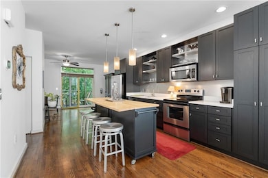 Kitchen featuring appliances with stainless steel finishes, open shelves, wood counters, dark wood-type flooring, and recessed lighting
