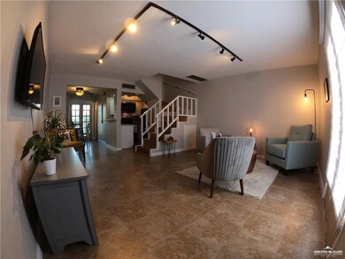 Living area featuring stairs, track lighting, baseboards, a ceiling fan, and stone finish floors