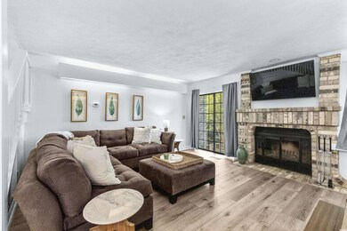 Living area featuring a fireplace, light wood-type flooring, and a textured ceiling
