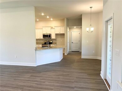 Kitchen featuring white cabinets, a chandelier, dark wood-style floors, light stone counters, and recessed lighting