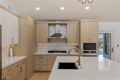 Kitchen featuring wall chimney exhaust hood, light