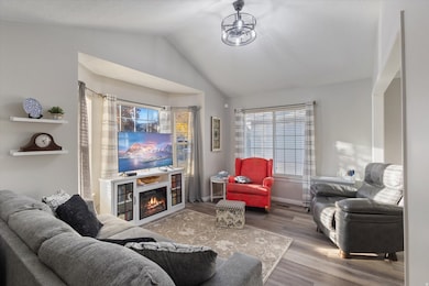 Living room with wood finished floors, vaulted ceiling, and a glass covered fireplace