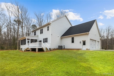Back of house featuring a yard, central air condition unit, stairway, a sunroom, and a garage