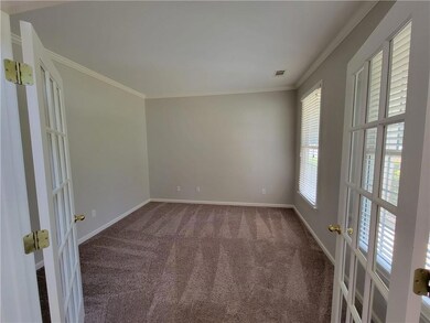Empty room with crown molding, visible vents, french doors, and carpet