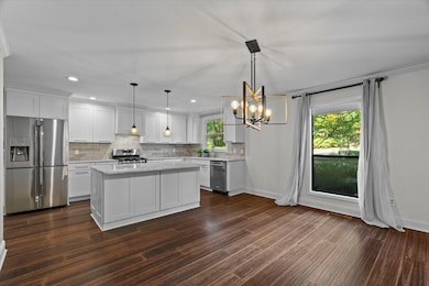 Kitchen with appliances with stainless steel finishes, a center island, a chandelier, white cabinetry, and recessed lighting