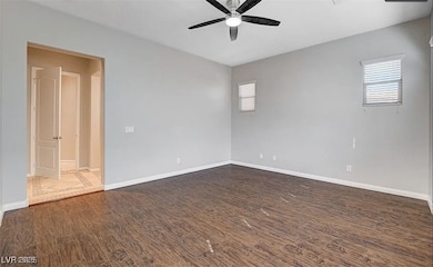 Unfurnished room featuring ceiling fan, dark wood-