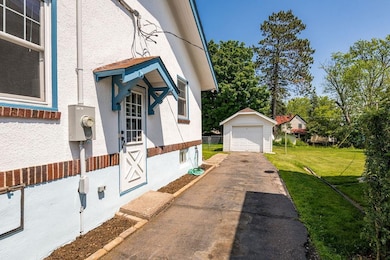 View of side of home with asphalt driveway, stucco siding, a garage, and an outbuilding