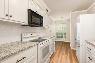 Kitchen featuring white appliances, white cabinets, ornamental molding, light wood finished floors, and tasteful backsplash